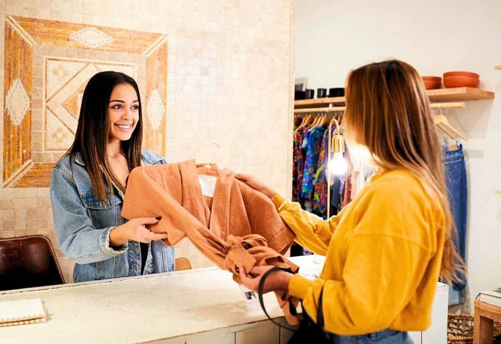 Cliente recebendo uma nova peça de roupa após o lançamento da campanha de marketing digital pela agência de marketing. Aprenda conosco como vender mais no inicio do ano.